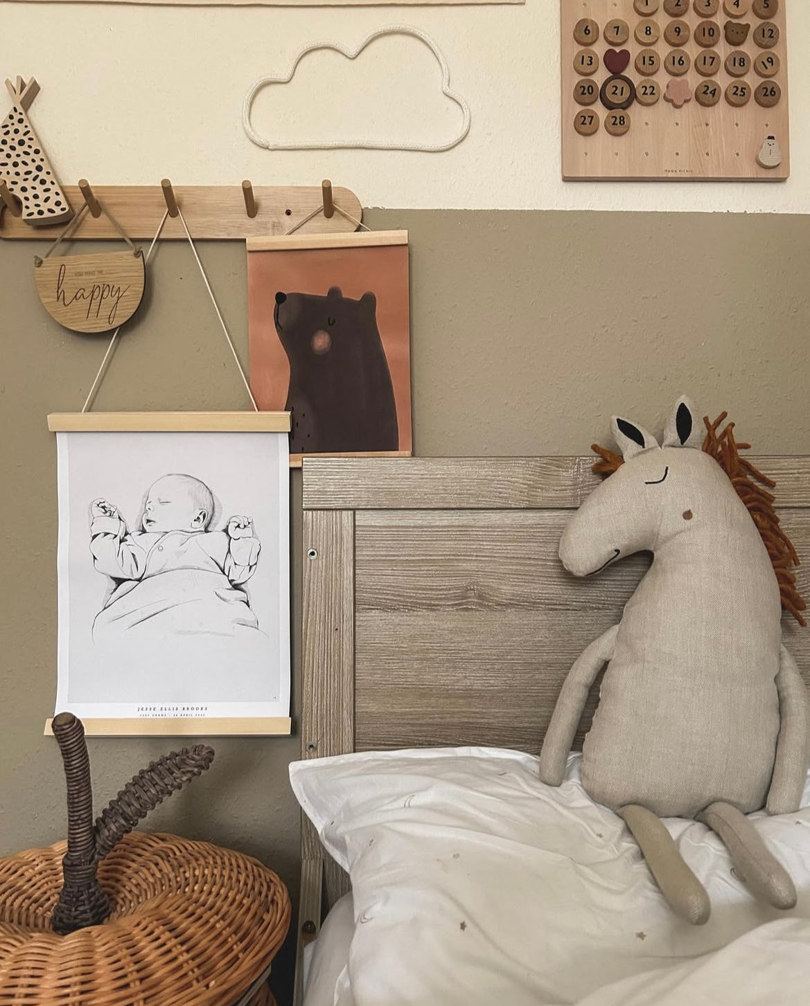 "Hand-drawn custom birth poster hanging in a wooden poster hanger in a child’s room